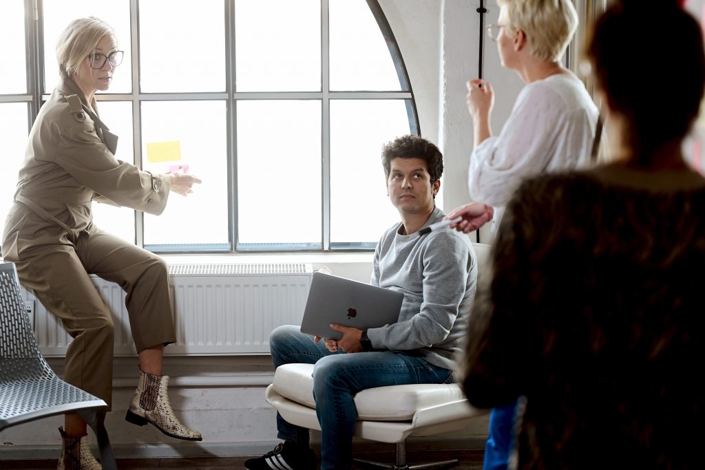 a woman pointing at a man sitting in a chair